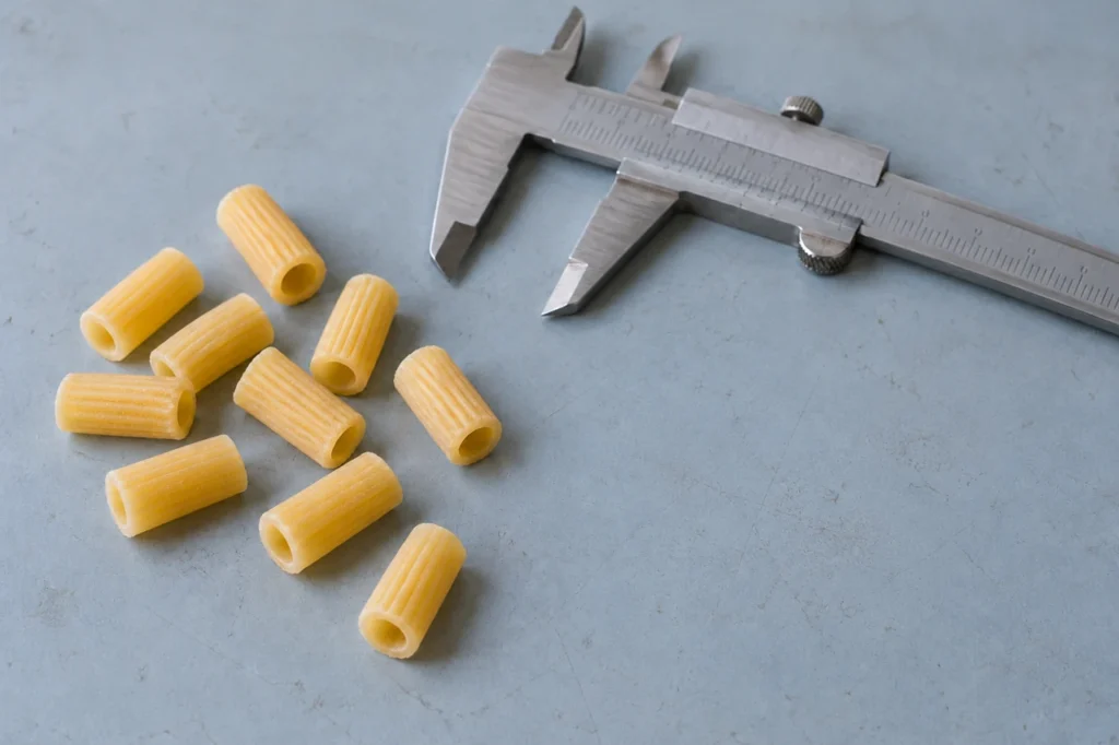 Concept illustration of short macaroni samples and a caliper for shape and size planning